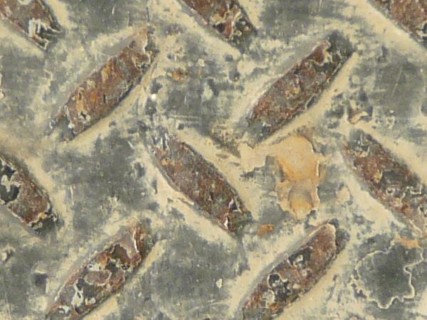 Old metal tread texture in brown tones with repeating pattern and very worn, dirty surface.